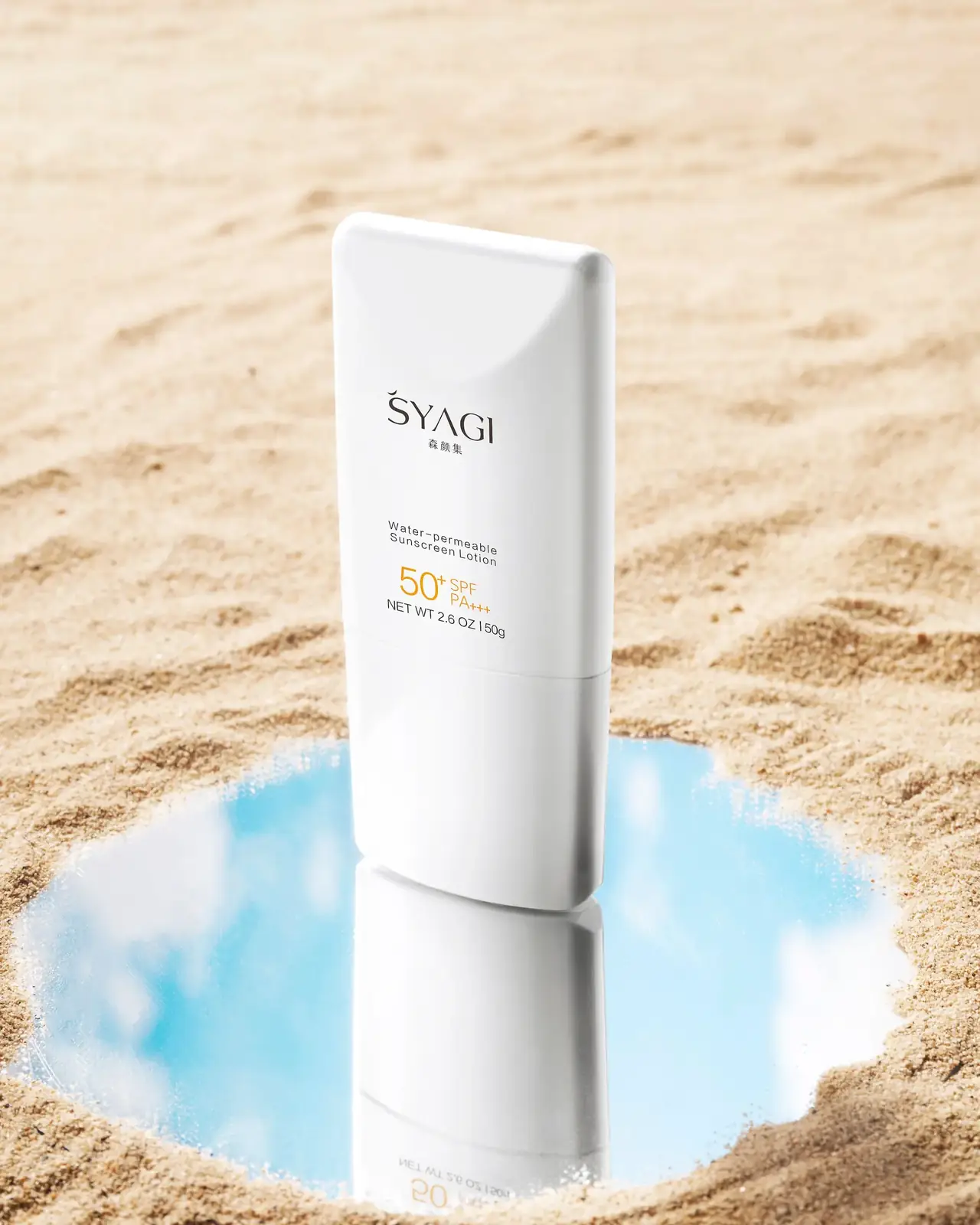تیوپ ضدآفتاب SPF ۵۰ روی ماسهی ساحل کنار آینهای که آسمان را بازتاب میدهد